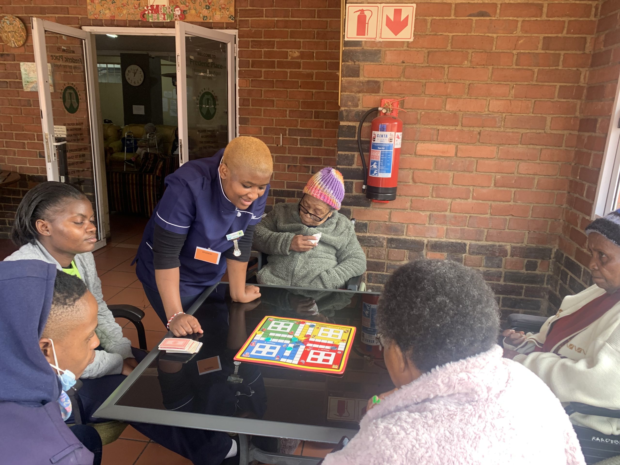 A staff member at Frederic Place sitting and talking with residents around a table